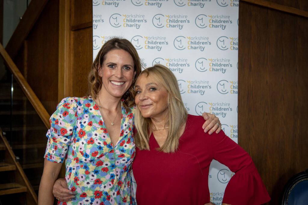 Charlotte Farrington, Yorkshire Children's Charity CEO and Helen Fielding, creator of Bridget Jones, in front of a Yorkshire Children's Charity banner